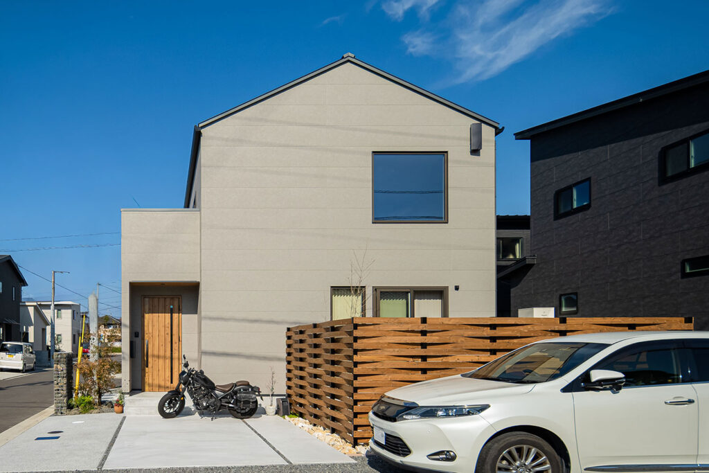 三角屋根とビルトインガレージ、駐車スペースを備えた愛媛の注文住宅の外観